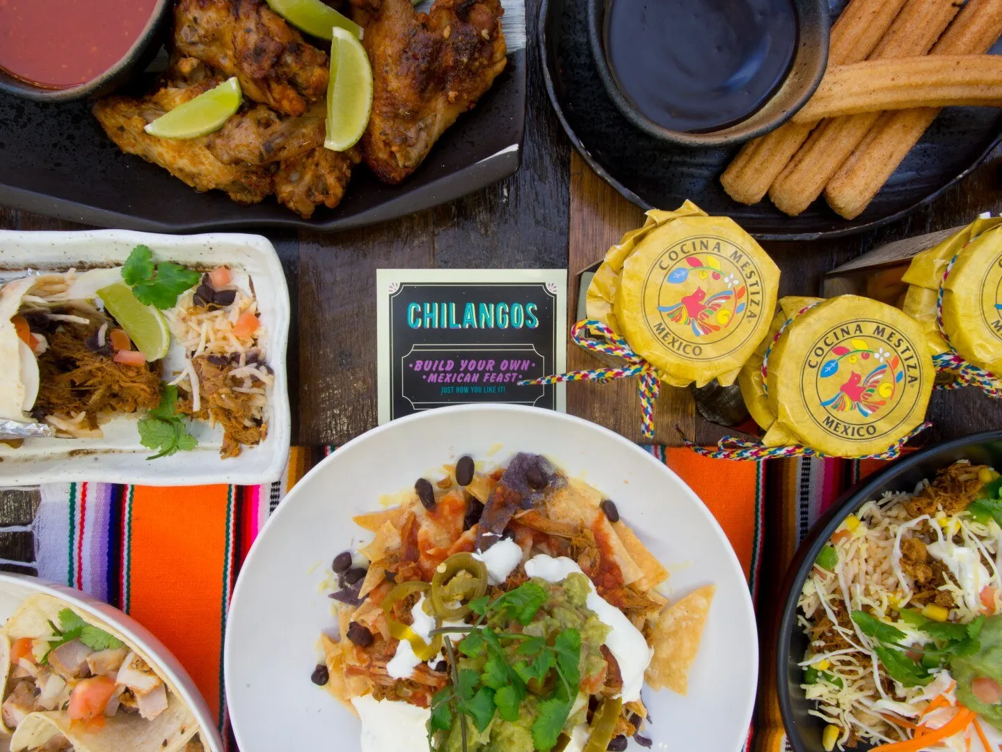 A spread of tacos, nachos, wings and churros